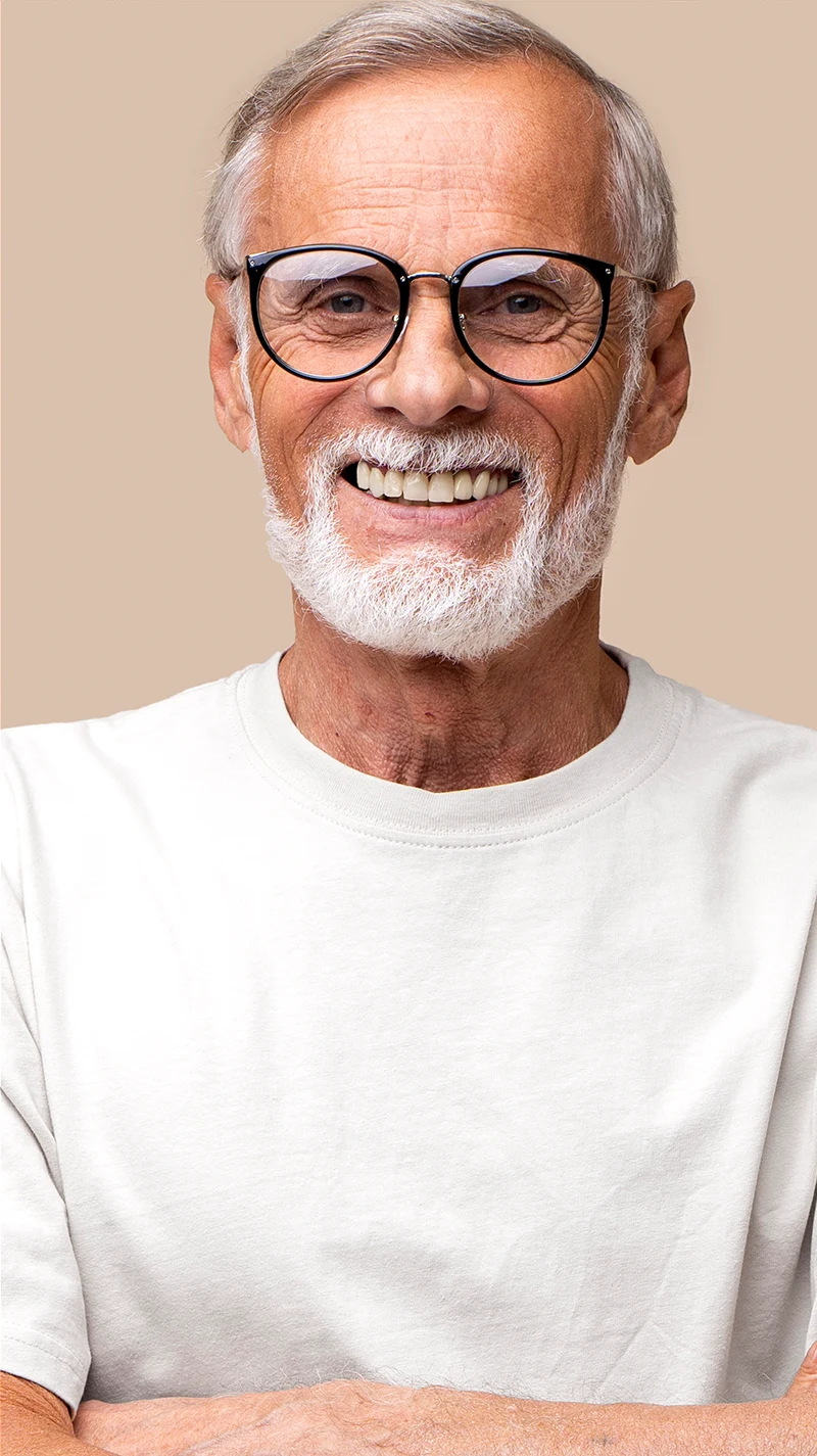 Ein älterer Mann mit weißem Haar sieht föhlich in die Kamera. Er trägt eine moderne, schwarze Brille